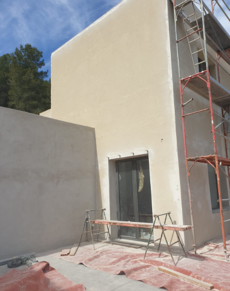 Lateral de la vivienda con el revestimiento aplicado y andamio de trabajo